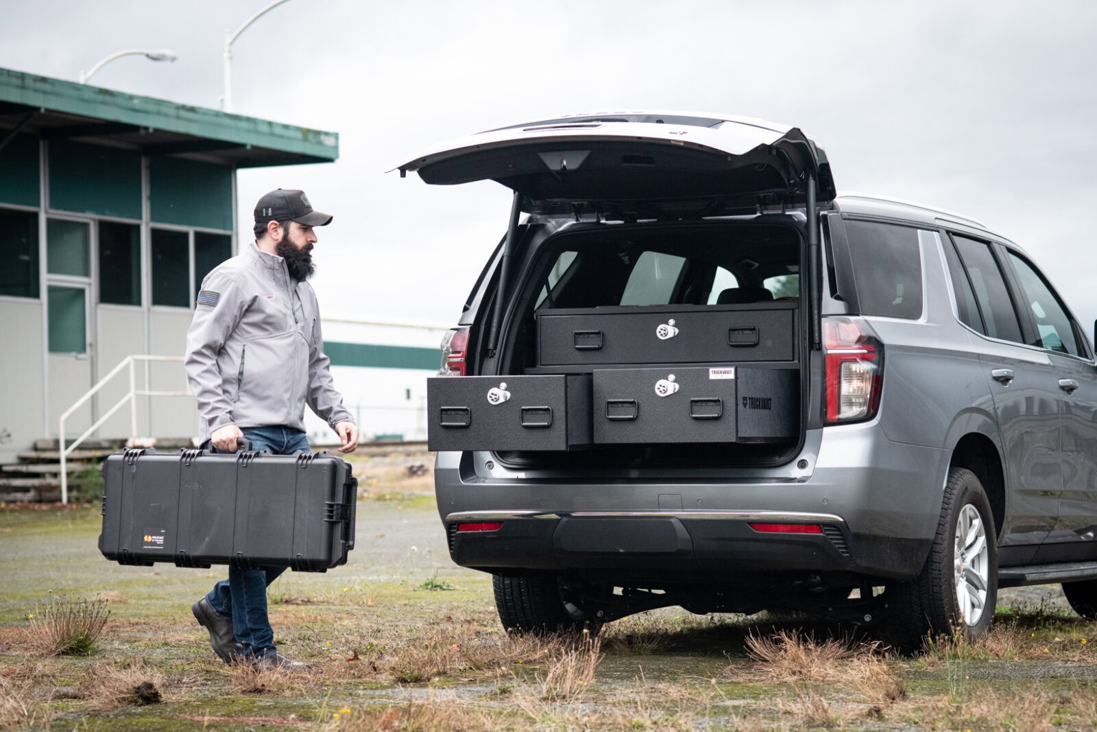 man loads tactical gear into a TruckVault SUV system