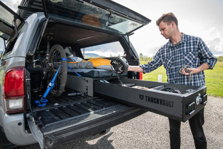 Overlander opens his CB1 drawer in his Toyota Tacoma. A bike is stored to the left of the unit and a mattress is secured to the top of the unit.