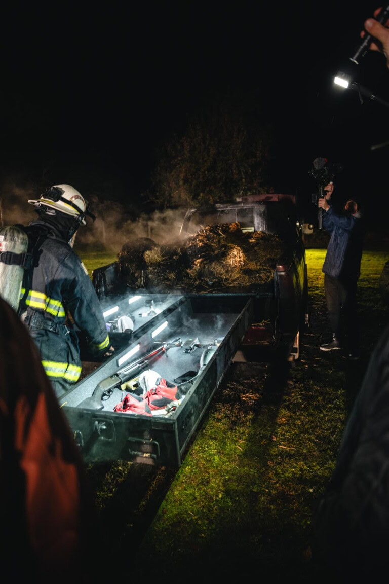 Firefighters test TruckVault's durability during burn and water trials at night. Open drawers reveal the contents are safe from the fire.