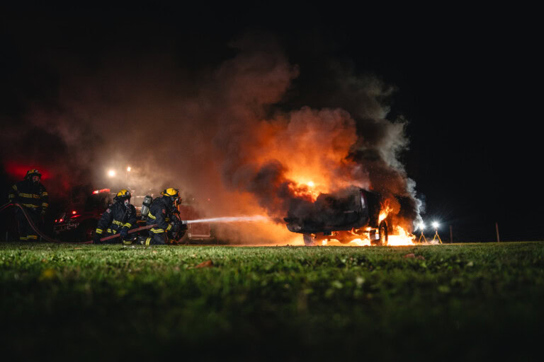 Firefighters extinguish burning truck during a nighttime fire product test for TruckVault.